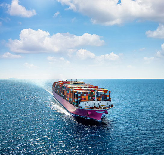 Aerial vertical front view of a heavy loaded container carrier ship sailing with speed over the open ocean